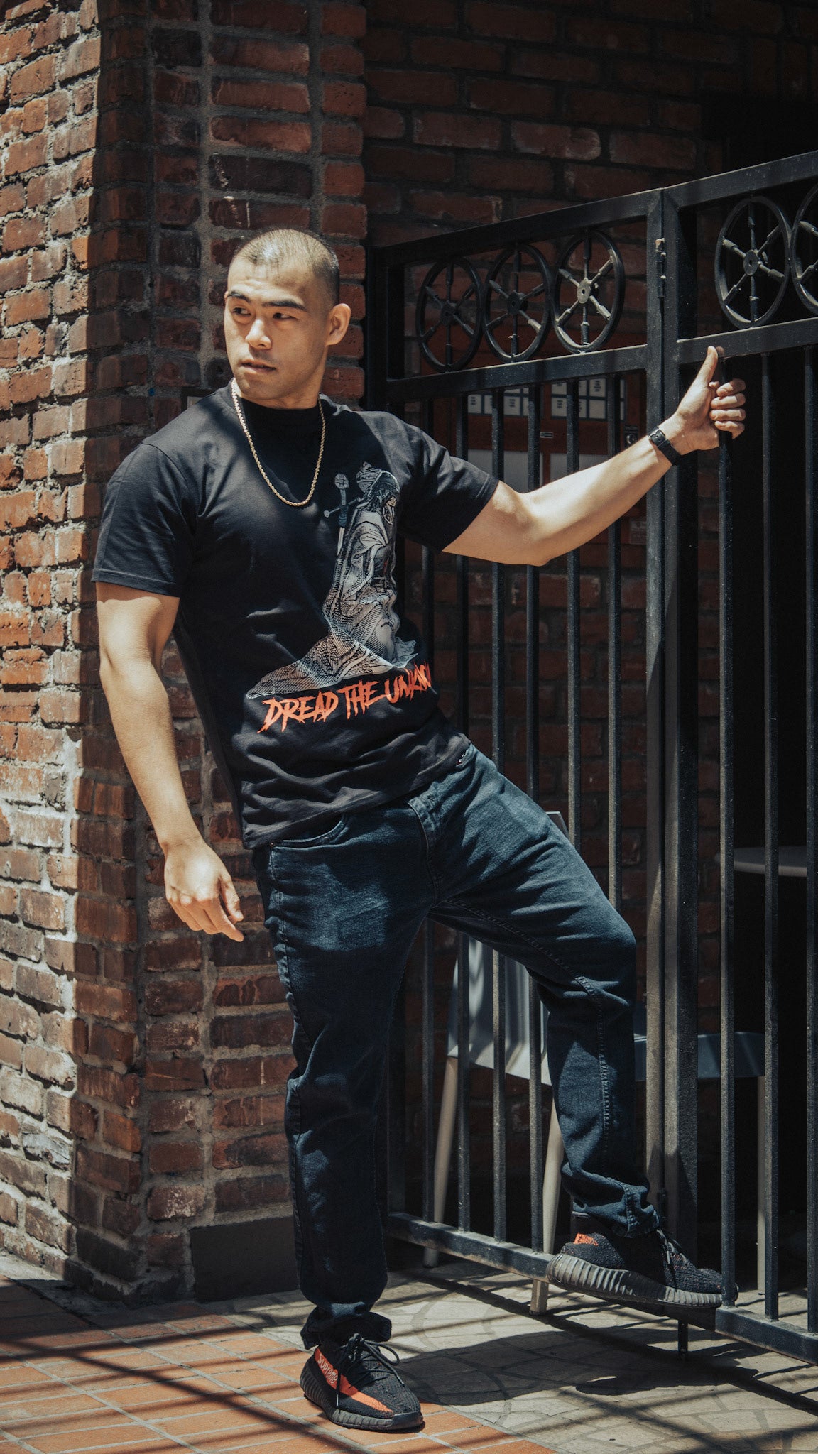Man wearing Cazcarro Dread the Unknown tee against a brick wall